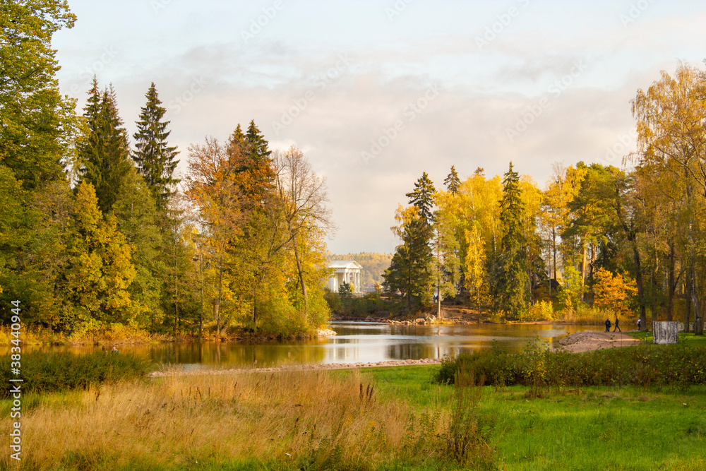 Autumn landscape with a lake, yellowed trees and a small white stand in the distance Autumn landscape with a lake, yellowed trees and a small white stand in the distance