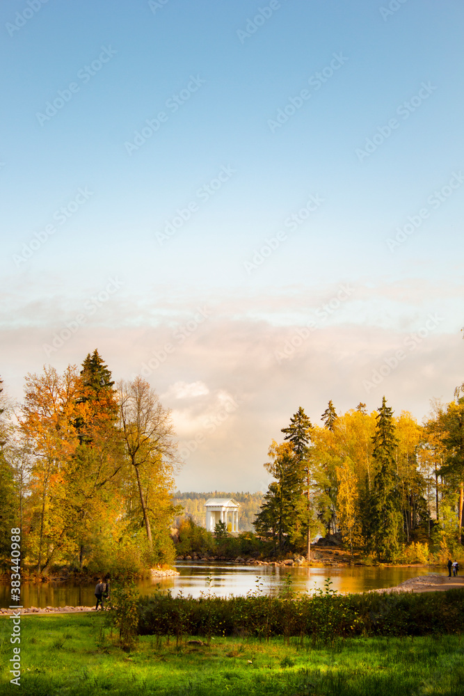 Autumn landscape with a lake, yellowed trees and a small white stand in the distance Autumn landscape with a lake, yellowed trees and a small white stand in the distance