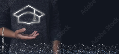 Fotografi Close up hand hold virtual gologram academic cap in dark background