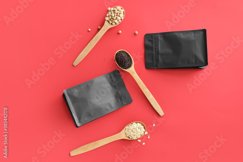 Bags and spoons with different groats on color background