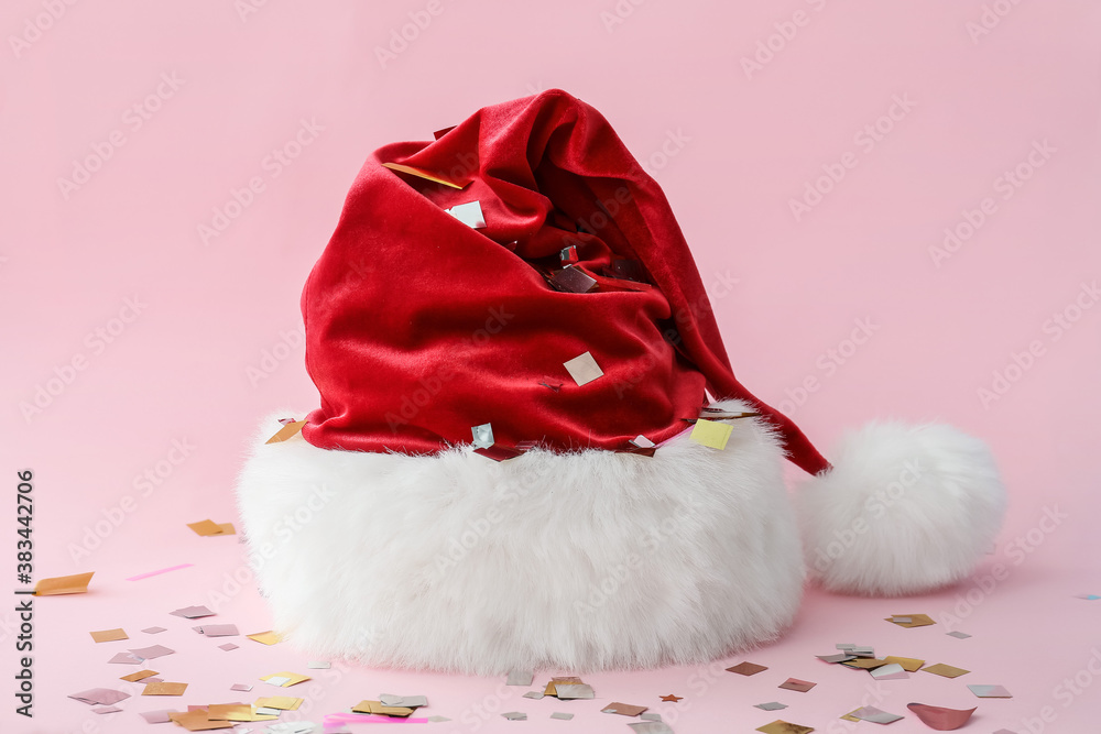 Santa Claus hat with confetti on color background Santa Claus hat with confetti on color background