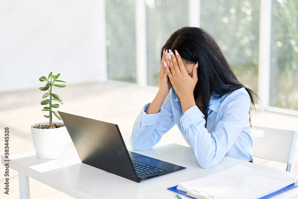 Stressed tired businesswoman closed face by two hands sitting in modern office Stressed tired businesswoman closed face by two hands sitting in modern office