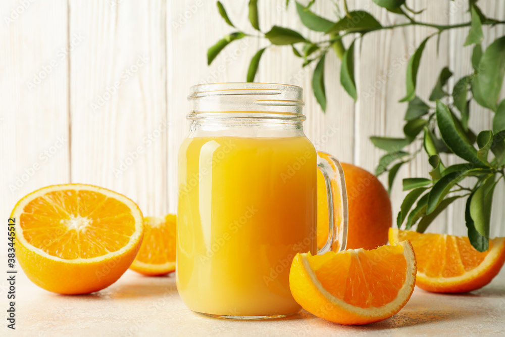 Glass jar with orange juice against white wooden background Glass jar with orange juice against white wooden background