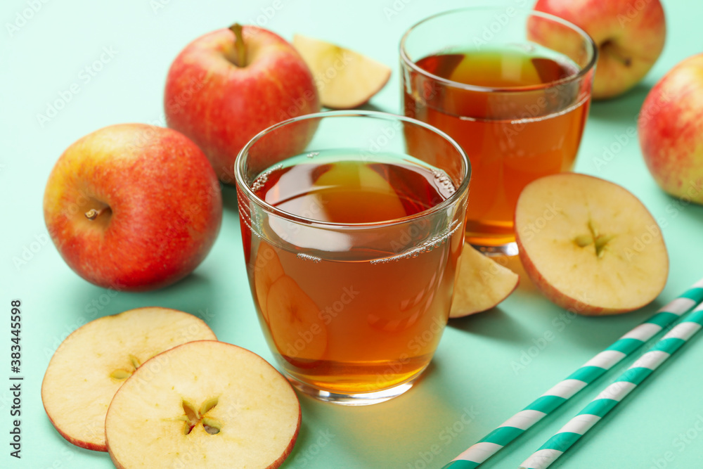 Apple slices, straws and glasses of apple juice on mint background Apple slices, straws and glasses of apple juice on mint background
