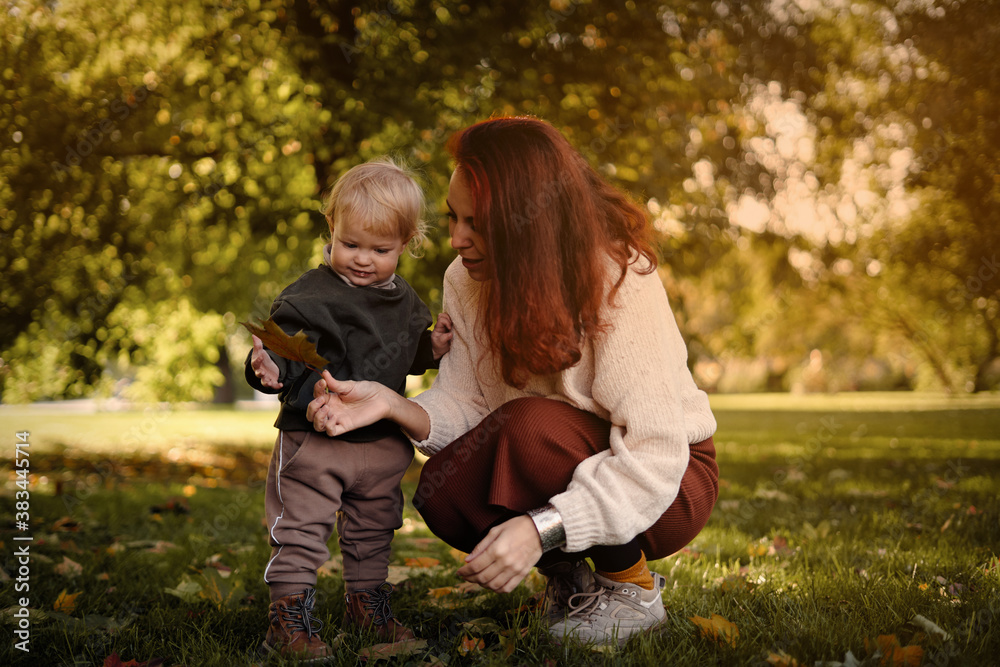 mother with a small child among the foliage of the trees play and rejoice mother with a small child among the foliage of the trees play and rejoice