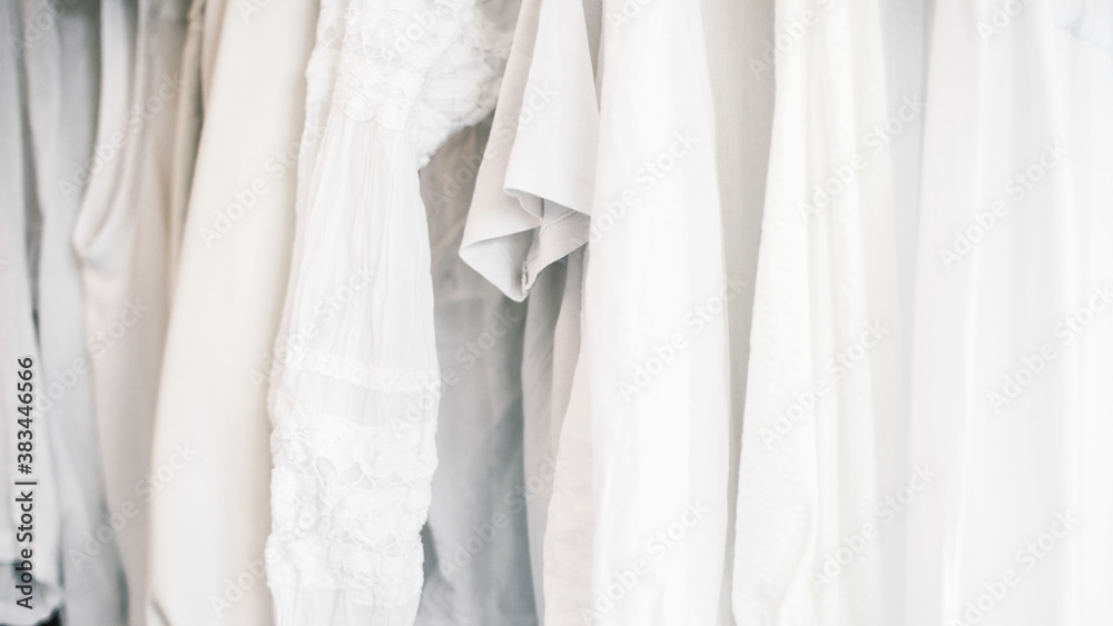 Different white clothes hanging on rail on blue background. Different white clothes hanging on rail on blue background.