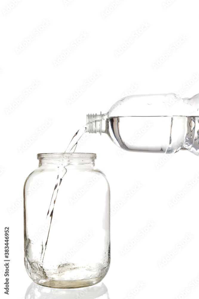 Pouring water into an empty glass jar on a white background Pouring water into an empty glass jar on a white background