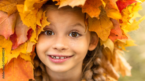 A little girl with a wreath of maple leaves on her head.