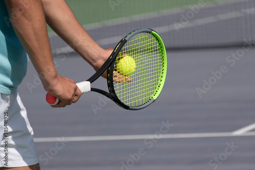 Tennis player with racket and ball on purple hard tennis court prepares to serve. Start of tennis game, match, tournament. Sports background with copy space. Selective focus