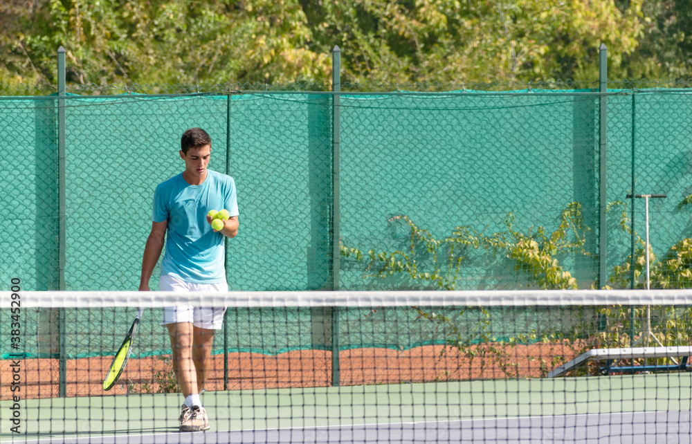 Professional tennis player on tennis court selects the ball for serve. Playing tennis on open hard courts. Sports background. Selective focus.