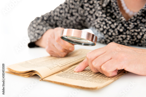 Foto An old man is holding a magnifying glass in hand to look up on an old yellowed b
