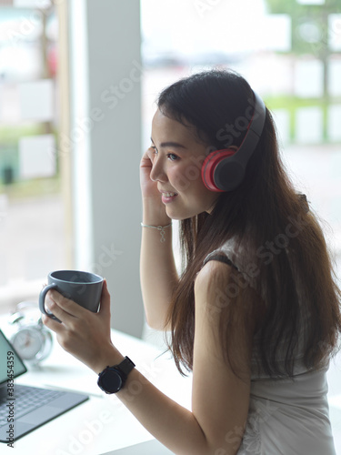 Female teenager relaxing with coffee cup and listening music with headphone