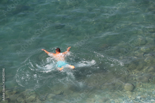 Swimming in the sea, beach vacation. Man diving in a clear blue water, top view