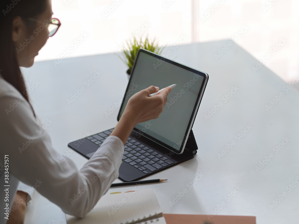 Female pointing on mock up tablet screen while working in office room Female pointing on mock up tablet screen while working in office room
