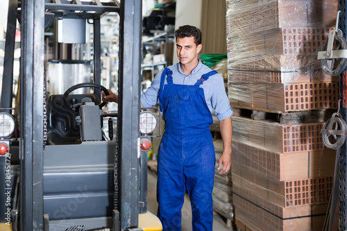 man in unifom is using cargo moving machine in the warehouse building store