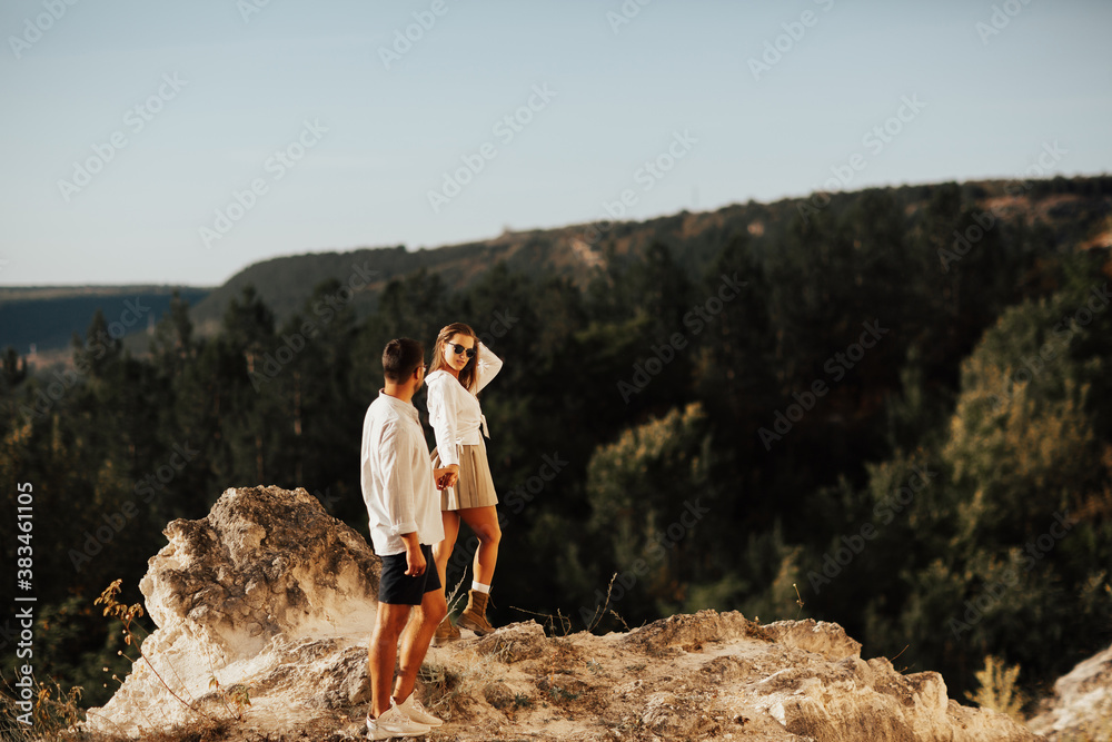 Young woman holding hand of her boyfriend while walking by rocky mountain. Couple enjoying a hike in nature. Follow me.