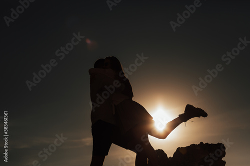 Man holding woman. Silhouettes Couple staying on the beach with sun rays on background. Copy space.