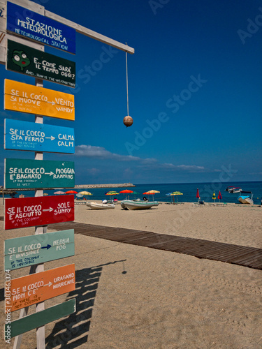 Coconut Weather Station, Lido La Grazia beach Parghelia, Tropea. Calabria. Italy. A funny way of telling the weather, meteorological station. In the background umbrellas and deck chairs