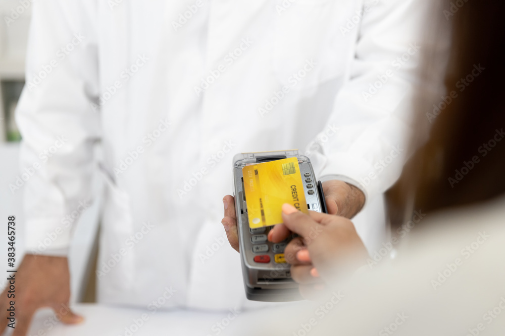 Customer making payment using credit card contactless with a credit card reader machine in modern pharmacy. NFC technology Customer making payment using credit card contactless with a credit card reader machine in modern pharmacy. NFC technology