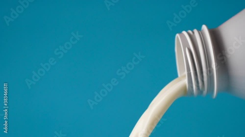 bottle of milk pouring- blue background- slow motion