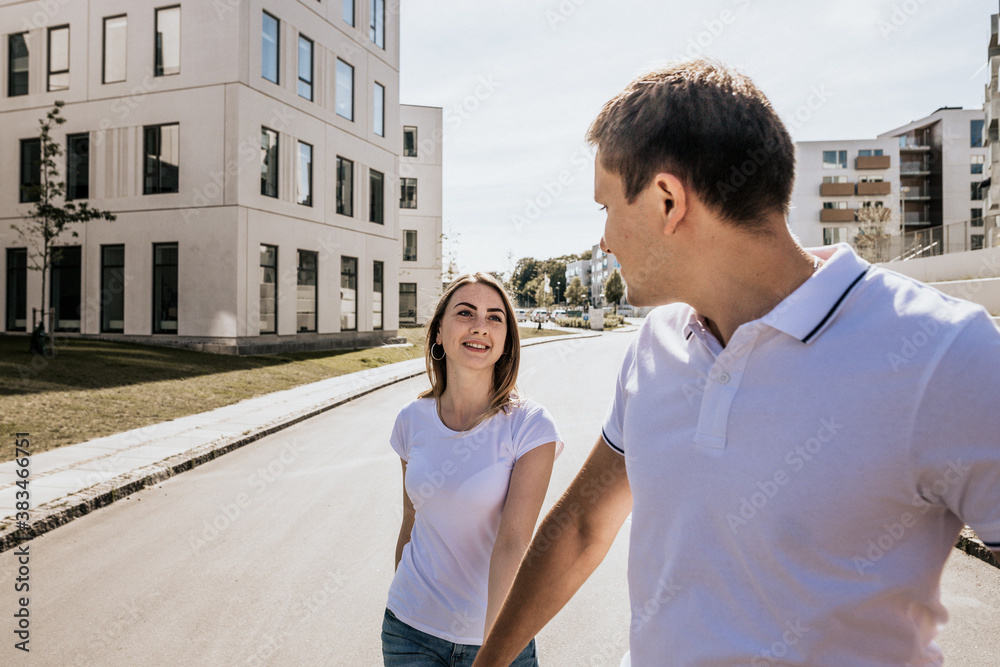 Fototapeta premium Close up of stylish couple in white T-shirt smiling while walking outdoors