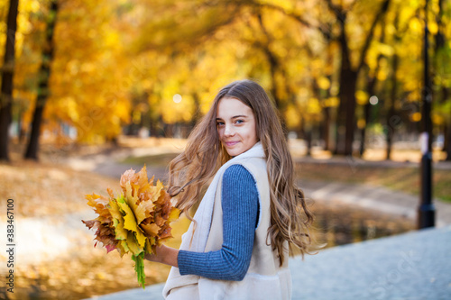 Young beautiful blonde girl surrounded autumn leaves