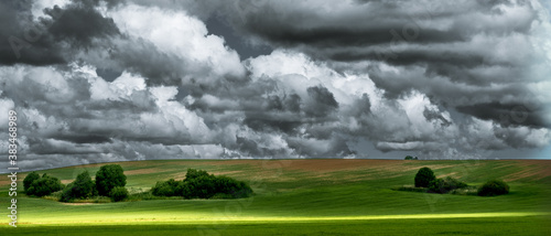 Stormy, dark clouds over green field.