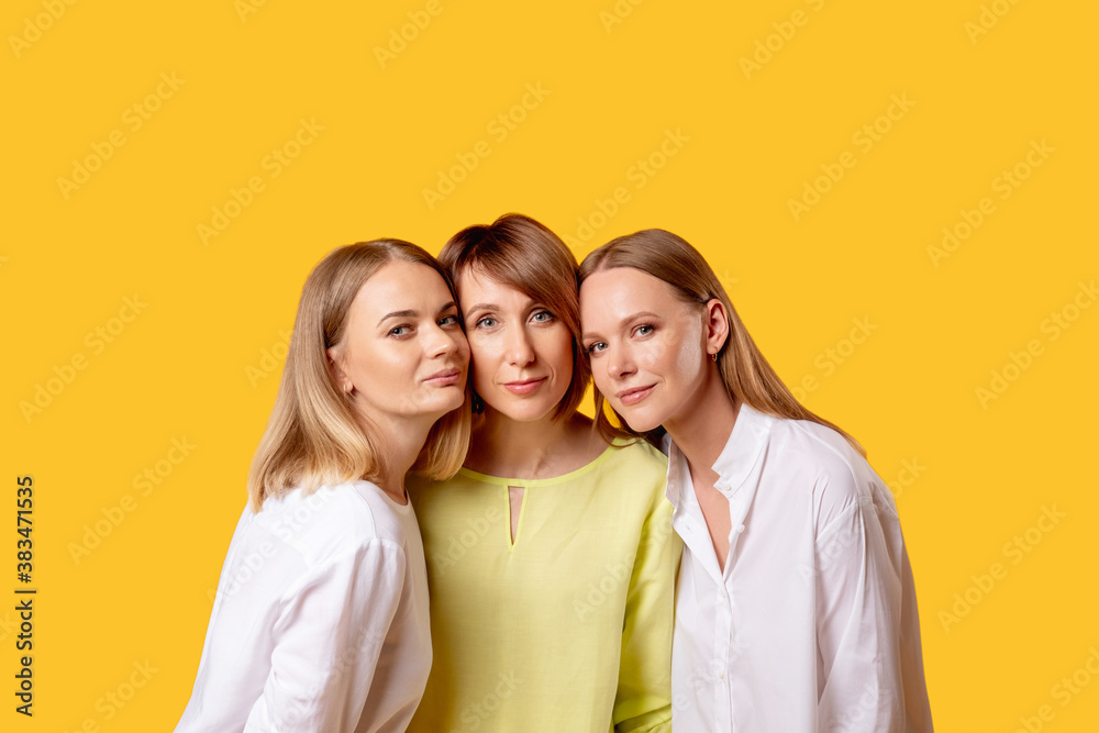 Family portrait. Mother daughters relationship. Love support. Three happy positive women together isolated on orange copy space background. Family portrait. Mother daughters relationship. Love support. Three happy positive women together isolated on orange copy space background.