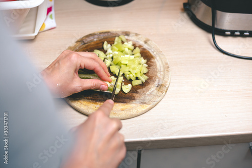 Woman's hands cutting fresh paprika on chopping board, over the shoulder view. Cooking at home concept.