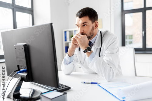 healthcare, medicine and people concept - male doctor with computer working at hospital