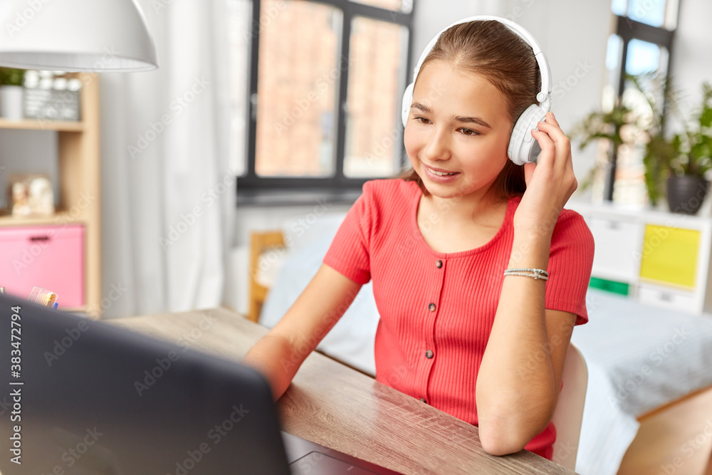 children, education and distant learning concept - happy smiling teenage student girl in headphones with laptop computer at home children, education and distant learning concept - happy smiling teenage student girl in headphones with laptop computer at home