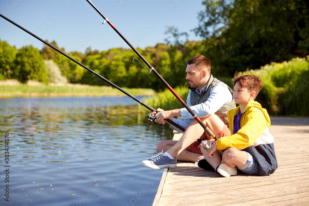 family, generation, summer holidays and people concept - happy smiling father and son with fishing rods on river berth family, generation, summer holidays and people concept - happy smiling father and son with fishing rods on river berth