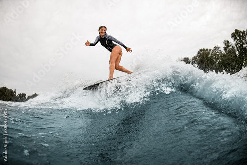handsome athletic woman stands on a surfboard and professionally rides on the wave