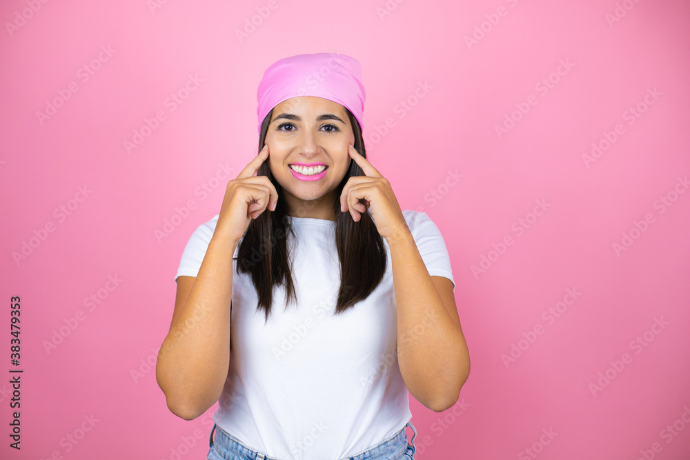 Young beautiful woman wearing pink headscarf over isolated pink background smiling confident showing and pointing with fingers teeth and mouth