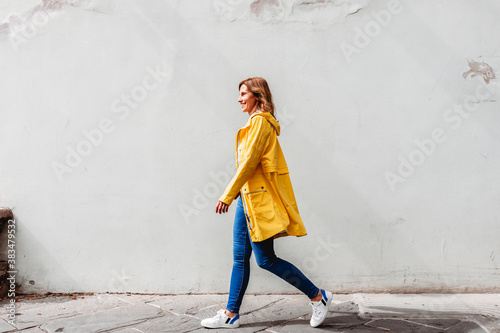 happy woman walking on a street in a city in front of a wall photo