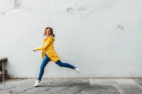 happy woman jumping in front of a wall in the city