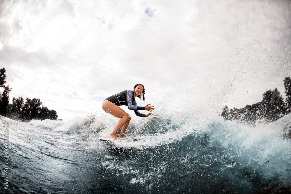 cheerful woman in wetsuit engaged in extreme sport and rides board on river wave cheerful woman in wetsuit engaged in extreme sport and rides board on river wave