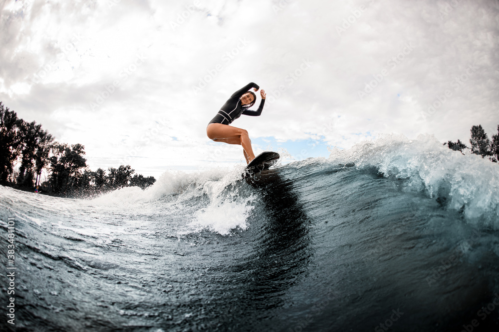 happy smiling woman riding the wave on surfboard on warm summer day