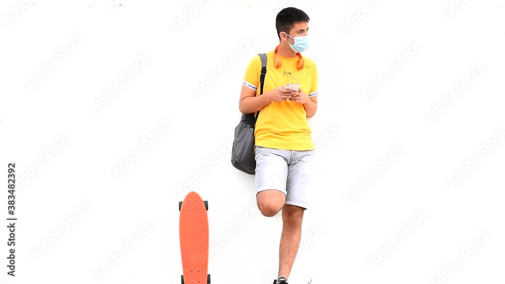 Teenager waiting leaning on the wall in a yellow shirt, with a skateboard and backpack. Teenager waiting leaning on the wall in a yellow shirt, with a skateboard and backpack.