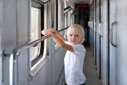 Cute blond boy traveling by train. Children in railroad car.