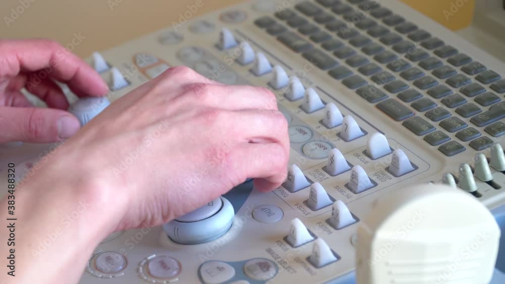 Close up of hands of young doctor working on ultrasound device Close up of hands of young doctor working on ultrasound device