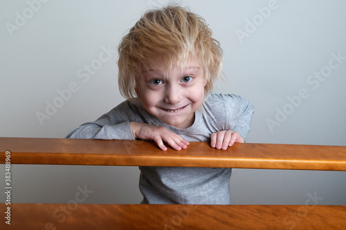 Smiling blond boy with leaned over the banister and looks down. Playing with children