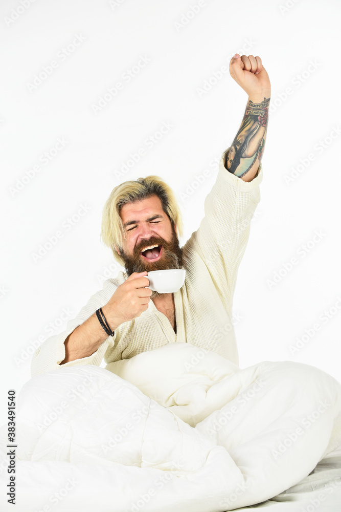 Obraz premium Man with beard in dressing gown. Guy in bath clothes hold coffee. Morning rituals concept. Tired man drinking coffee. Every morning begins with coffee. Bachelor in bathrobe