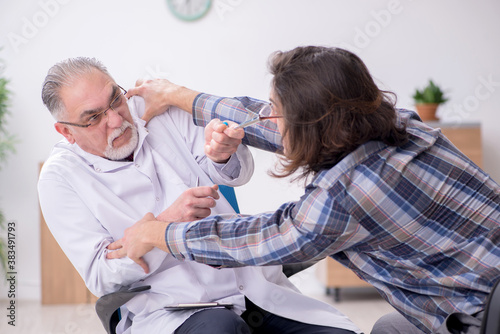 Young male psychopath and experienced doctor in madhouse photo