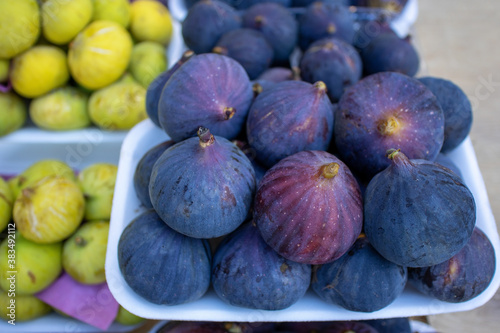 Fresh ripe blue and yellow figs on the counter of a fruit and vegetable store.