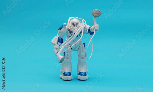 Fototapeta Naklejka Na Ścianę i Meble -  Figurine astronaut holding headphones in his hands while standing on a blue background. The concept is to listen to space music.