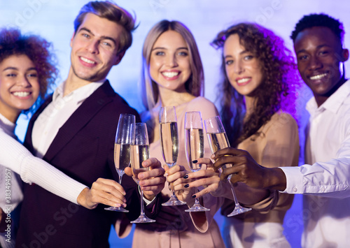 Friends Raising Glasses Toasting Looking At Camera During Party Indoors