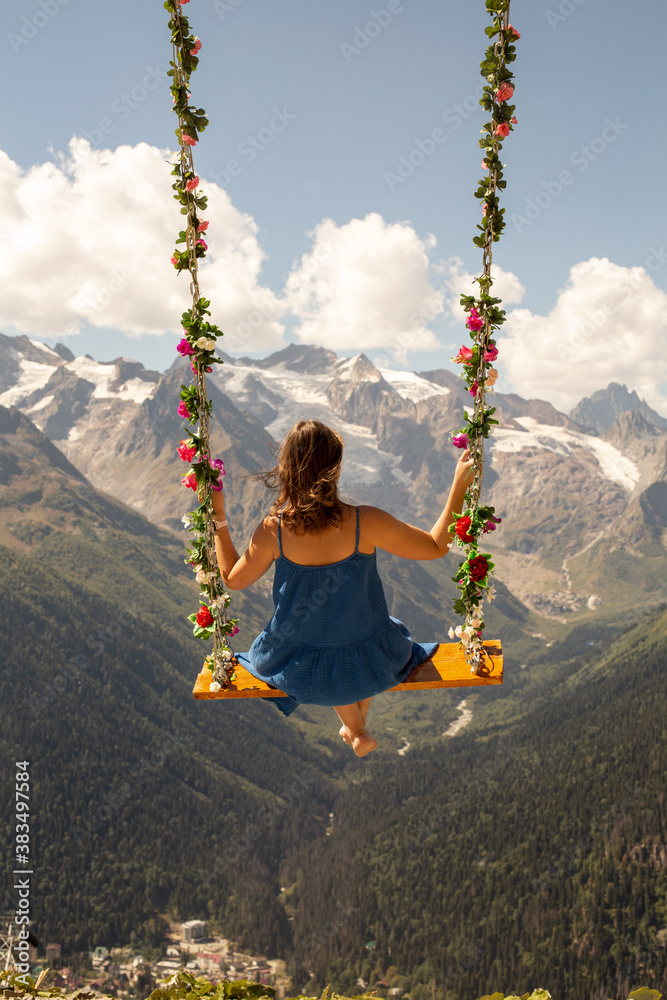 Woman on a heavenly swing in the mountains