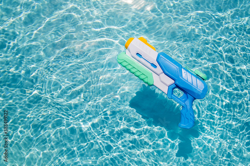 A child's blue water gun floats in the pool. A toy for playing in the pool or on the beach