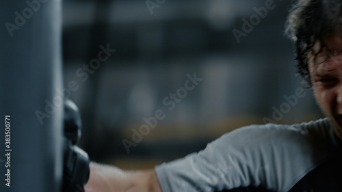 Progressive fighter training hits in fitness center. Kickboxer exercising at gym